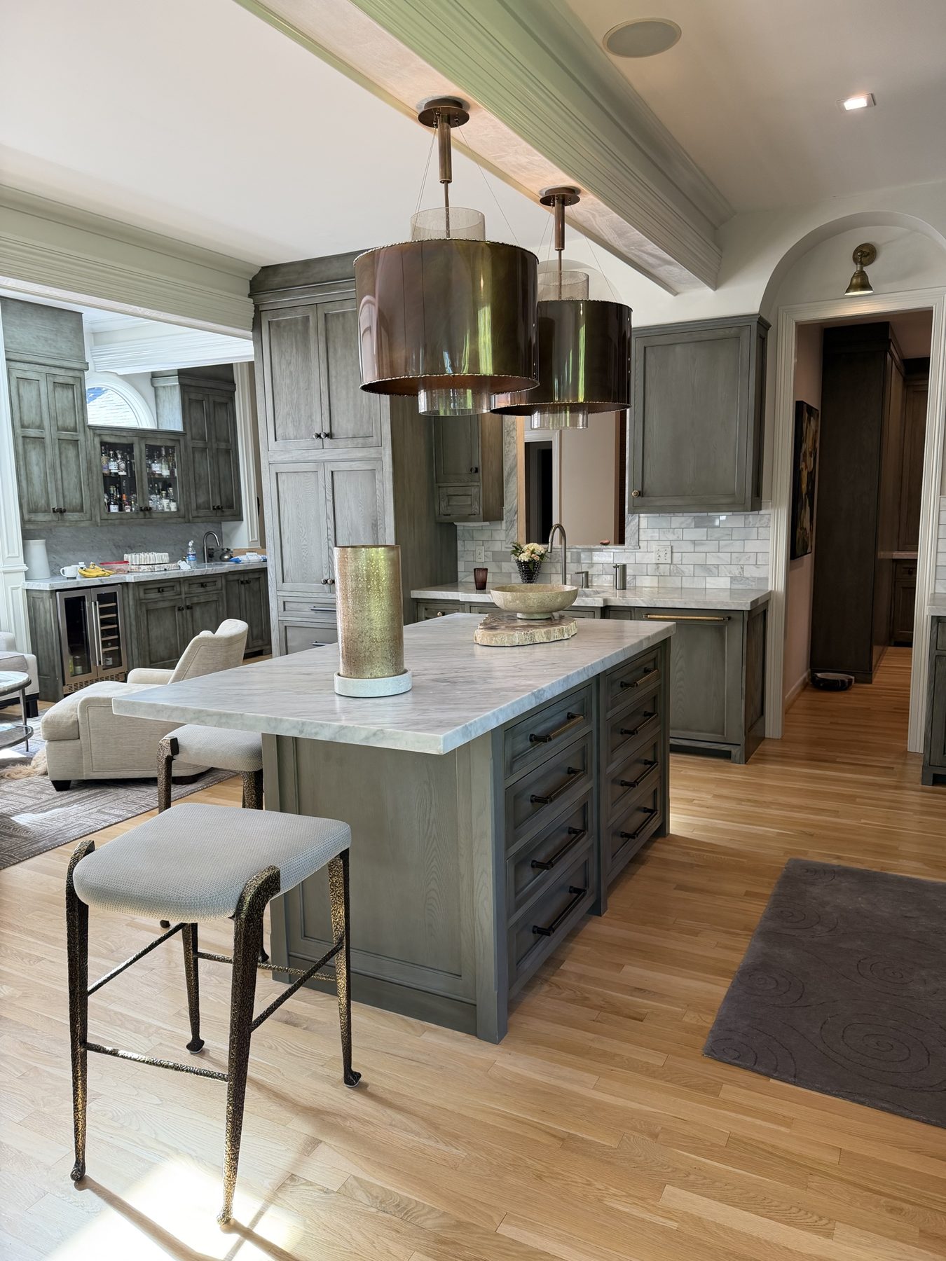 Kitchen island with inset drawers and a marble top beneath copper pendants