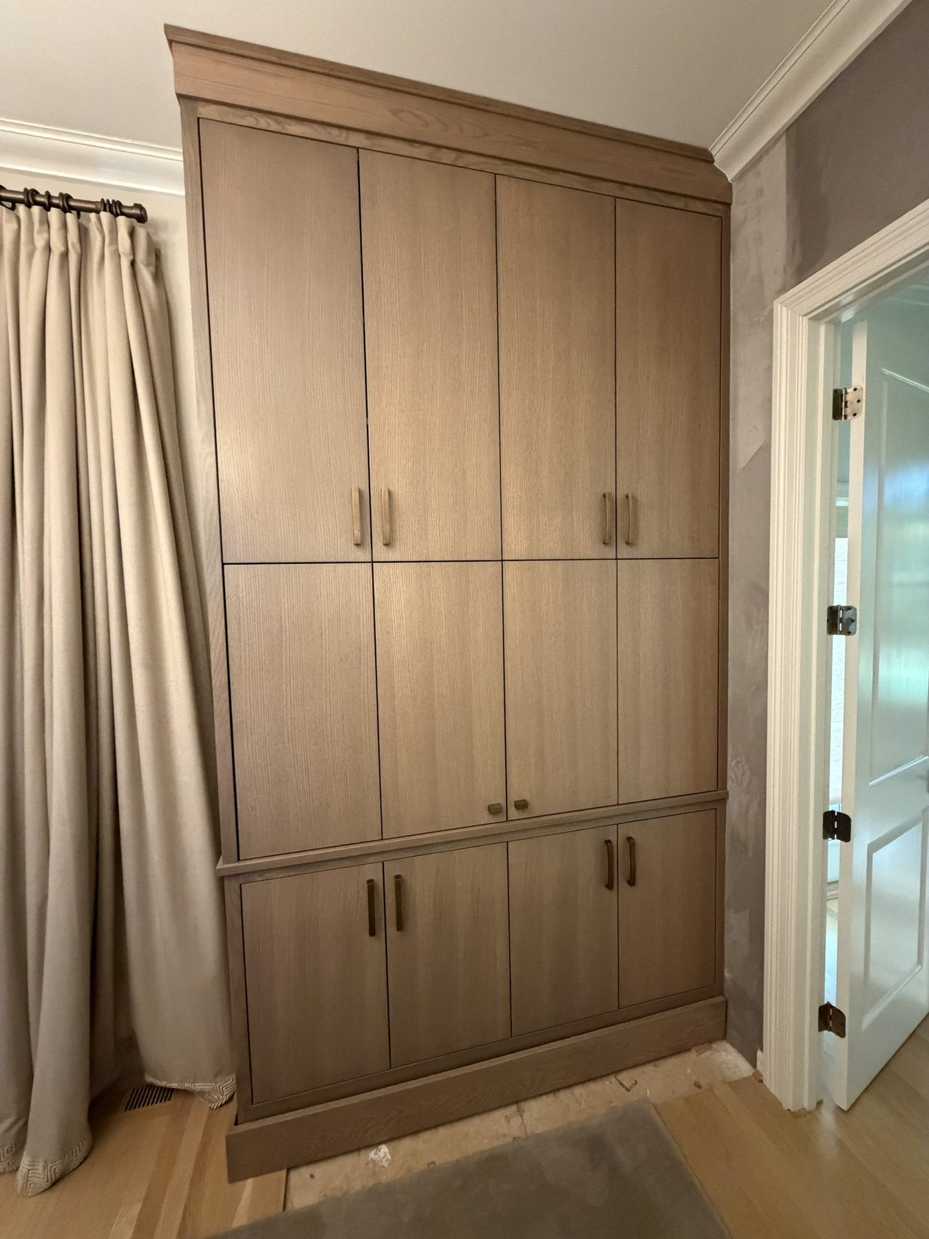 Floor-to-ceiling white oak wardrobe with brass pulls